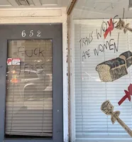 As frases "FUCK TERFS" ("FODAM COM AS TERFS") e "TRANS WOMEN ARE WOMEN" ("MULHERES TRANS SÃO MULHERES") escritas na porta e na janela.